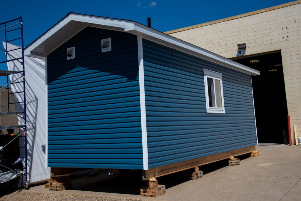 blue home exterior 1 image on Honouring a Legacy: Trade Winds to Success Unveils Eco-Smart Small Home with Cree Artist Lance Cardinal